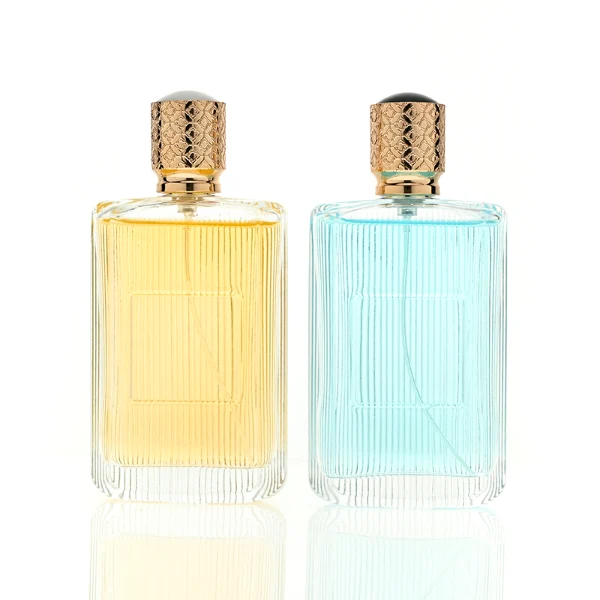 A rectangular clear glass perfume bottle detailed with distinct vertical grooves and a smooth central label indentation, paired with a cylindrical golden plastic cap featuring an intricate textured pattern.