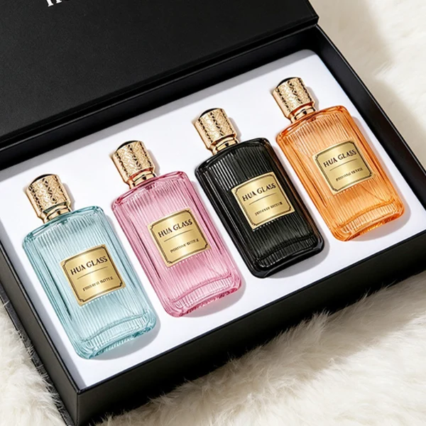 A rectangular clear glass perfume bottle detailed with distinct vertical grooves and a smooth central label indentation, paired with a cylindrical golden plastic cap featuring an intricate textured pattern.