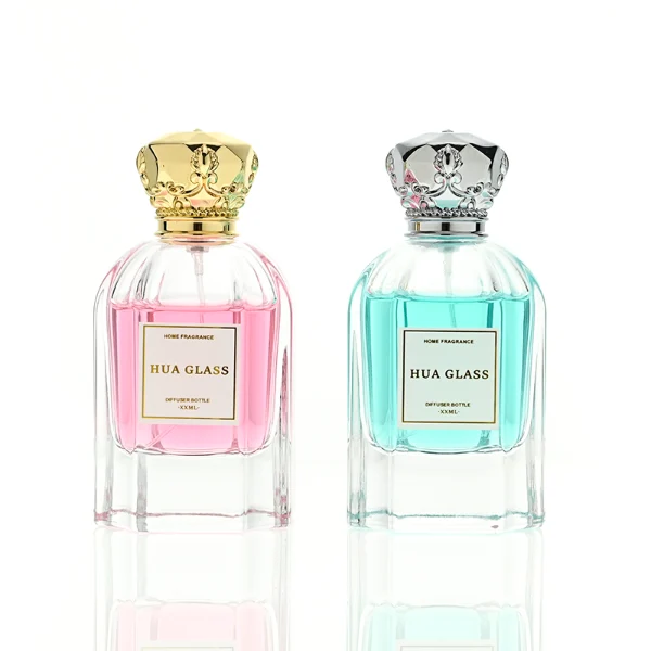 A hexagonal clear glass perfume bottle with structured vertical facets along the body, paired with an ornate, crown-shaped heavy metallic Zamac cap available in polished gold or silver.