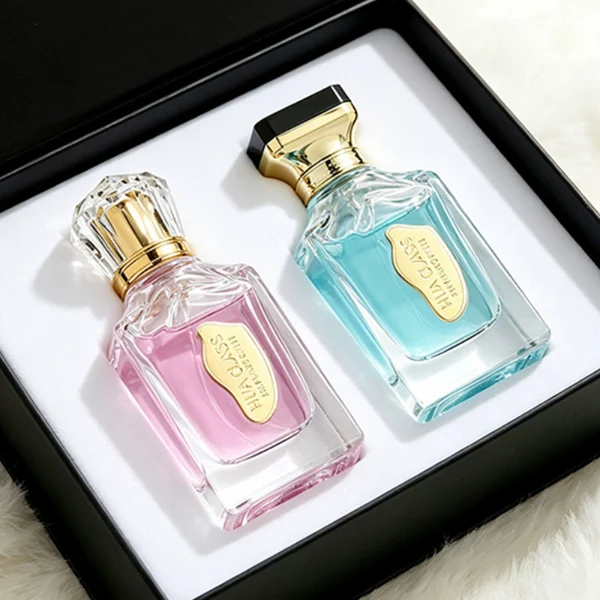 A thick-bottomed rectangular clear glass perfume bottle with faceted upper corners, shown with two cap variations: a crystal-clear faceted crown-shaped cap with a gold core, and a flared gold cap topped with a flat black cube block.