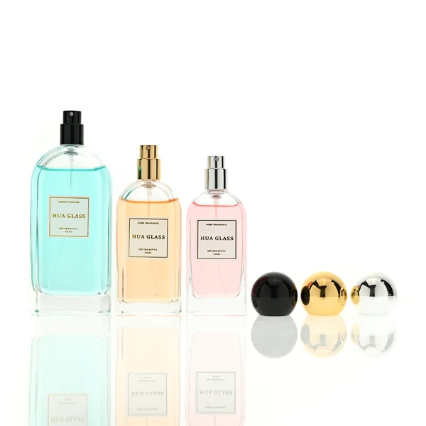 a set of rectangular clear glass perfume bottles features rounded shoulders and a thick glass base, each paired with a smooth, highly reflective spherical ball cap available in glossy black, metallic gold, or polished silver.