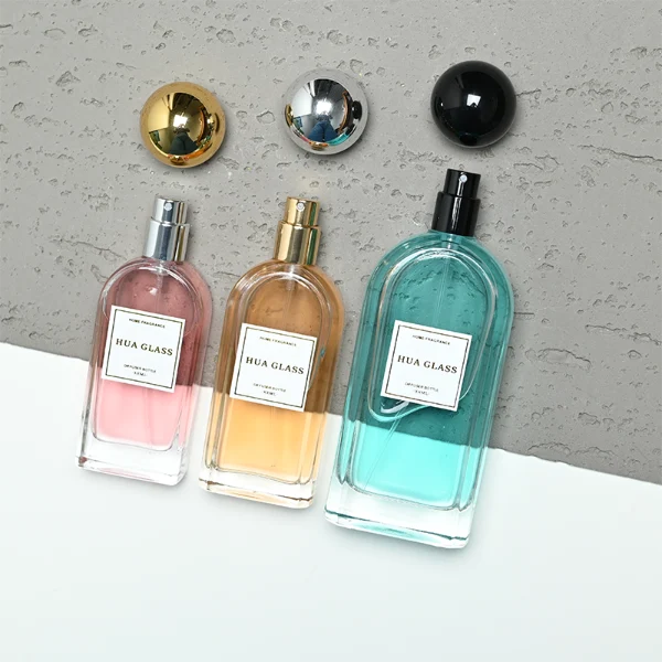 a set of rectangular clear glass perfume bottles features rounded shoulders and a thick glass base, each paired with a smooth, highly reflective spherical ball cap available in glossy black, metallic gold, or polished silver.