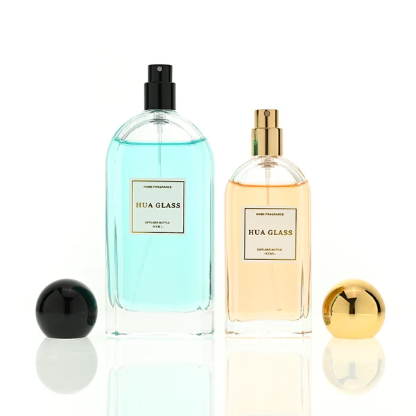 a set of rectangular clear glass perfume bottles features rounded shoulders and a thick glass base, each paired with a smooth, highly reflective spherical ball cap available in glossy black, metallic gold, or polished silver.
