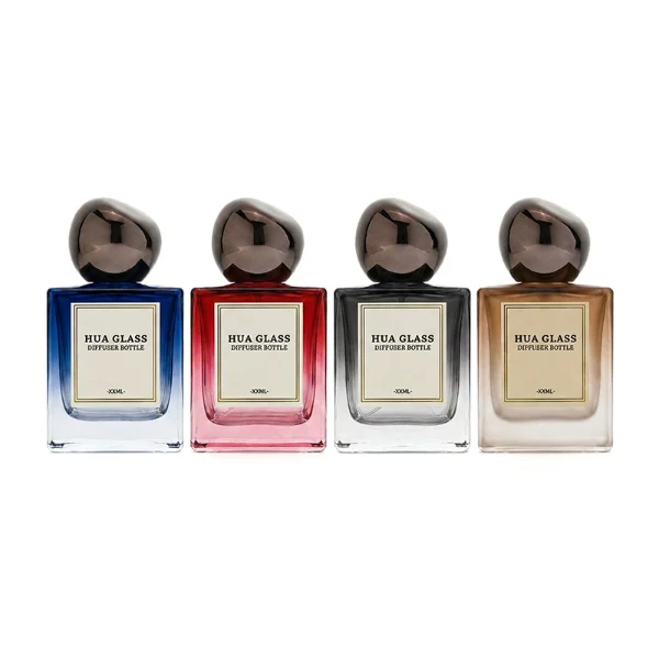 In the image, a thick-bottomed cube clear glass perfume bottle with a structured square silhouette is paired with a smooth, asymmetrical oval ellipse plastic cap available in polished gold, glossy black, or metallic brown finish.