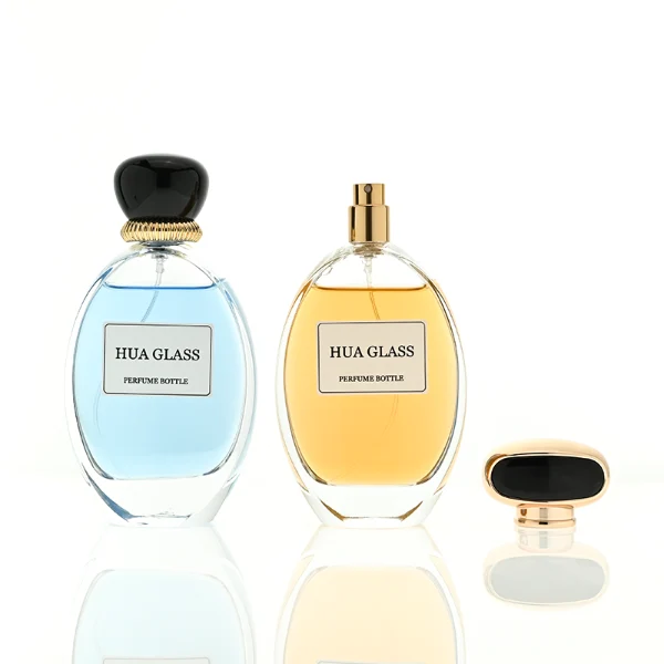 a globular curved clear glass perfume bottle features an oval silhouette with a heavy base, paired with a smooth, pebble-shaped plastic cap available in glossy solid black with a ribbed gold collar, or a flat-oval black design encased in a gold border.