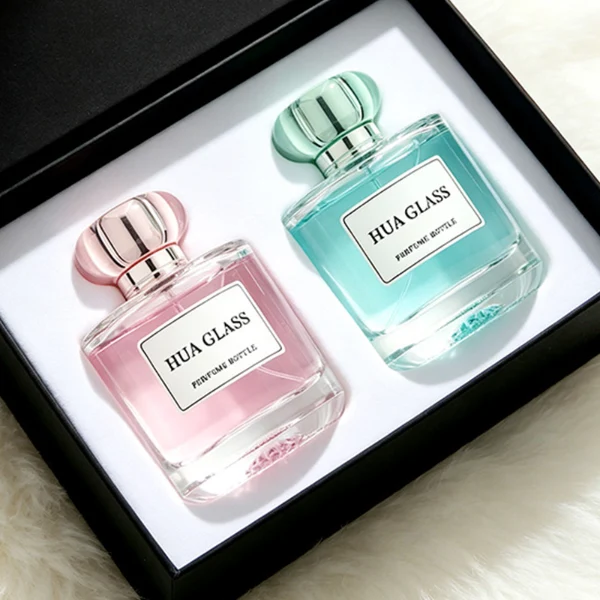 Based on the text description for image_128ca8.png, a clear square glass perfume bottle features rounded shoulders and a substantial, thick glass base, paired with a uniquely styled plastic cap available in pink-and-silver or blue-and-silver accents.