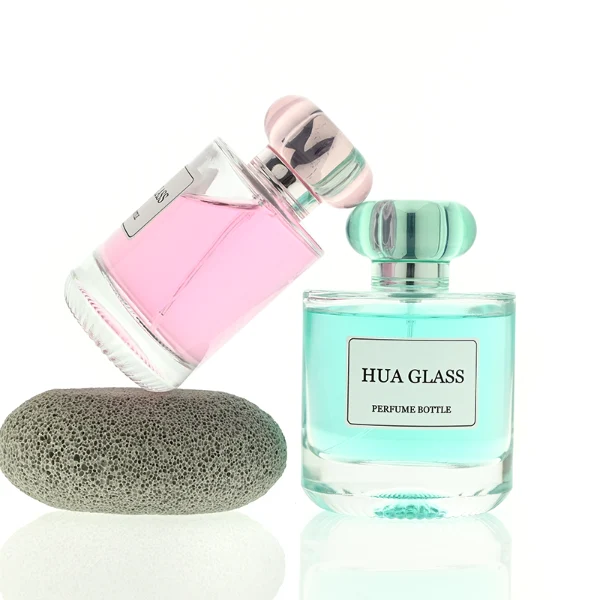 Based on the text description for image_128ca8.png, a clear square glass perfume bottle features rounded shoulders and a substantial, thick glass base, paired with a uniquely styled plastic cap available in pink-and-silver or blue-and-silver accents.