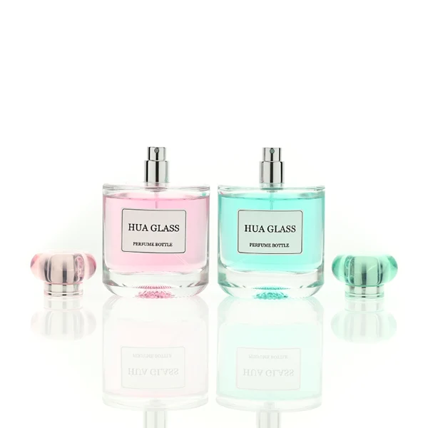 Based on the text description for image_128ca8.png, a clear square glass perfume bottle features rounded shoulders and a substantial, thick glass base, paired with a uniquely styled plastic cap available in pink-and-silver or blue-and-silver accents.