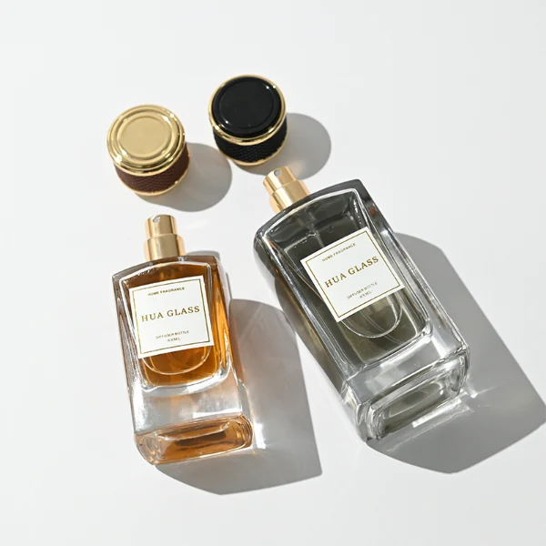 a clear rectangular glass perfume bottle features rounded shoulders and a thick square base, paired with a textured cylindrical plastic cap detailed with a micro-diamond knurled pattern and bordered by shiny gold metallic trim, available in black-and-gold or brown-and-gold finishes.