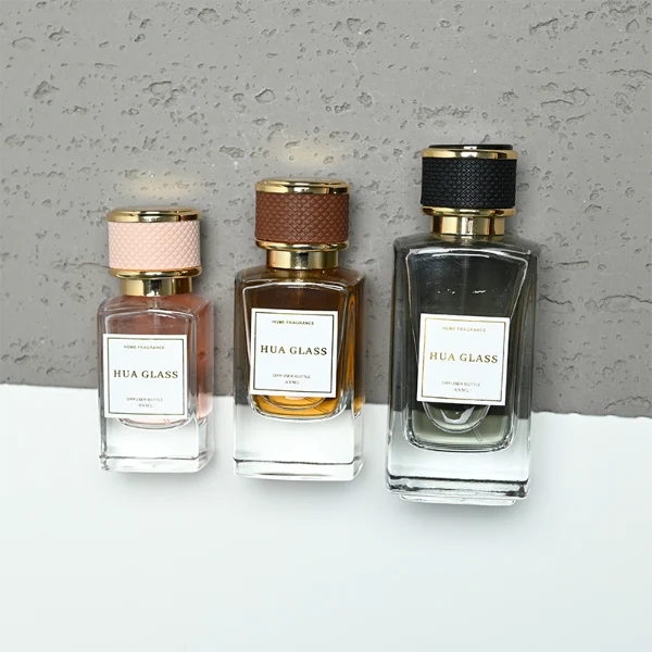 a clear rectangular glass perfume bottle features rounded shoulders and a thick square base, paired with a textured cylindrical plastic cap detailed with a micro-diamond knurled pattern and bordered by shiny gold metallic trim, available in black-and-gold or brown-and-gold finishes.