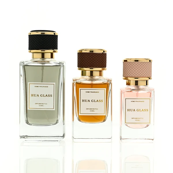 a clear rectangular glass perfume bottle features rounded shoulders and a thick square base, paired with a textured cylindrical plastic cap detailed with a micro-diamond knurled pattern and bordered by shiny gold metallic trim, available in black-and-gold or brown-and-gold finishes.