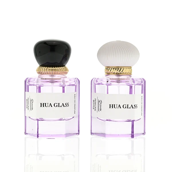 a hexagonal perfume bottle crafted from semi-translucent purple glass features a structured angular silhouette, paired with a pebble cobblestone-shaped plastic cap. The cap is available as either a smooth glossy black or a textured, vertically-ribbed matte white dome, both sitting atop an elegant, braided metallic gold collar.