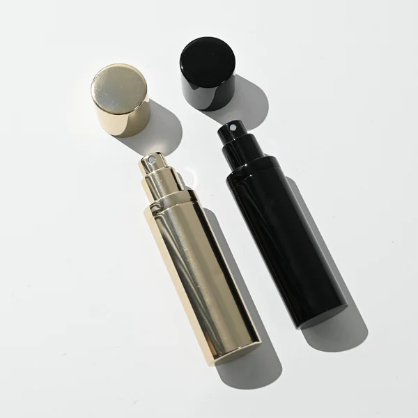 a sleek and ultra-slim 10ml travel-sized cylindrical perfume atomizer bottle features a seamless all-metallic exterior, paired with a matching magnetic cylindrical cap, presented in a high-gloss polished gold finish and a glossy solid black finish.