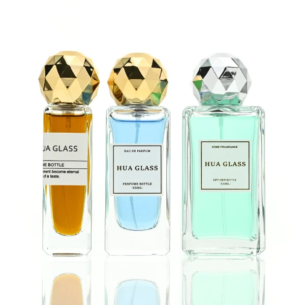 a collection of tall, thick-walled rectangular clear glass perfume bottles in various sizes is paired with a striking, multi-faceted geometric spherical ball cap featuring a disco-ball style design, available in polished metallic gold or silver finishes.