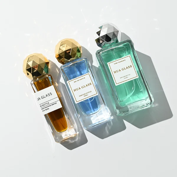 a collection of tall, thick-walled rectangular clear glass perfume bottles in various sizes is paired with a striking, multi-faceted geometric spherical ball cap featuring a disco-ball style design, available in polished metallic gold or silver finishes.