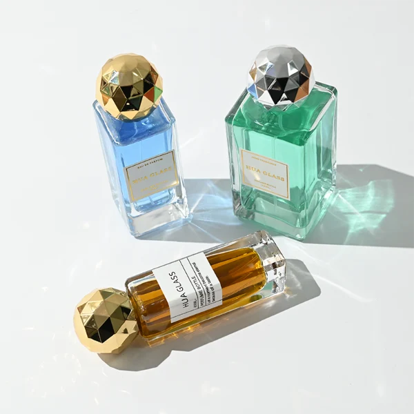 a collection of tall, thick-walled rectangular clear glass perfume bottles in various sizes is paired with a striking, multi-faceted geometric spherical ball cap featuring a disco-ball style design, available in polished metallic gold or silver finishes.
