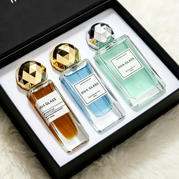 a collection of tall, thick-walled rectangular clear glass perfume bottles in various sizes is paired with a striking, multi-faceted geometric spherical ball cap featuring a disco-ball style design, available in polished metallic gold or silver finishes.