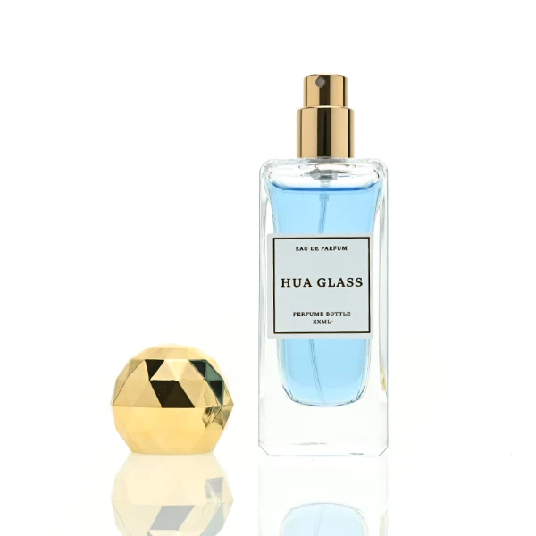 a collection of tall, thick-walled rectangular clear glass perfume bottles in various sizes is paired with a striking, multi-faceted geometric spherical ball cap featuring a disco-ball style design, available in polished metallic gold or silver finishes.