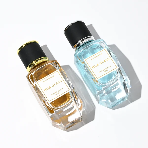 a classic rectangular clear glass perfume bottle with a heavy, thick base and faceted edges is paired with a matte black cylindrical cap. The cap is bordered at the top and bottom by a polished metallic ring, available in a bright gold or silver finish.