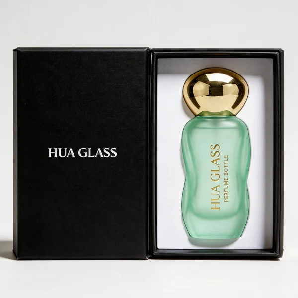 Three clear glass perfume bottles featuring smoothly curved organic shapes and heavy transparent bases, filled with olive green, pale pink, and light green liquids. The bottles are topped with smooth, pebble-like bulbous round caps, displayed in glossy black, polished metallic gold, and high-shine metallic silver finishes.