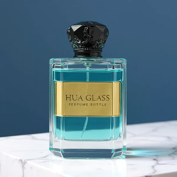 Two flat rectangular clear glass perfume bottles are shown with faceted, angled bottom corners and thick glass bases, holding light blue and amber liquids. Each bottle features a subtle debossed rectangular label panel on the front and is topped with an ornate, heavy Zamac crown-motif cap with a faceted dome, finished in glossy black and polished gold.
