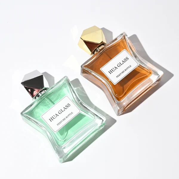 Two clear rectangular glass perfume bottles with a distinctively sculpted waisted design holding amber and light green liquids are shown. Each bottle features a central square white label and is topped with an asymmetrical, irregular multifaceted geometric cap featuring sharp reflective angles, presented in polished gold and high-shine chrome silver finishes.