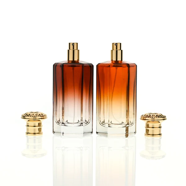 HUA0439 perfume bottle, luxury heavy-base polyhedral angular glass bottle with translucent deep multi-color gradient finish, featuring a crown-shaped flared hourglass solid Zamak cap with an intricately sculpted silver-colored glossy metallic finish, modern elegant fragrance packaging design available in 50ml and 100ml