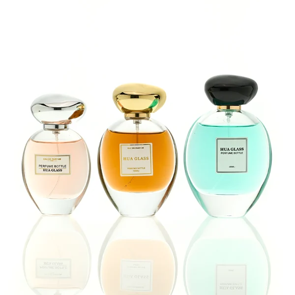 HUA0442 perfume bottle features a clear round curved glass body with a heavy base and is crowned with a modern premium pebble cobblestone-shaped silver or black plastic cap. Designed for wholesalers, it offers 30ml, 50ml, 75ml, and 100ml capacity options, delivering an elegant design that balances aesthetic refinement with durability for diverse fragrance lines.