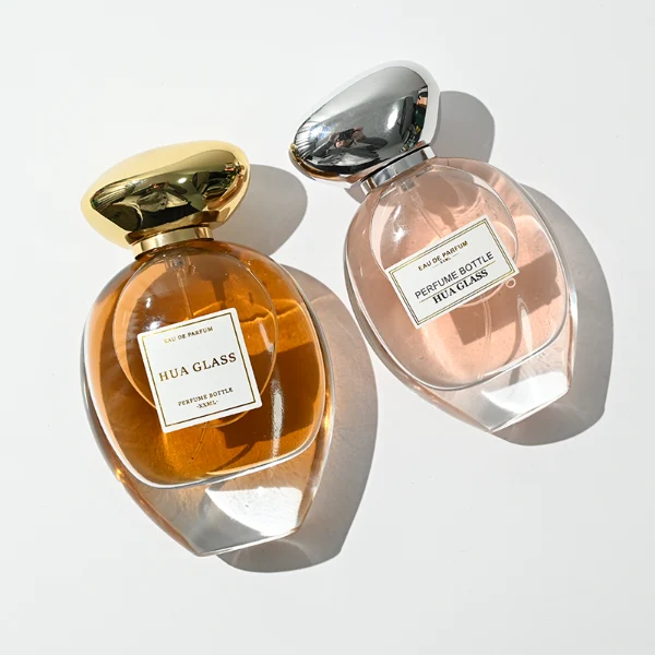 HUA0442 perfume bottle features a clear round curved glass body with a heavy base and is crowned with a modern premium pebble cobblestone-shaped silver or black plastic cap. Designed for wholesalers, it offers 30ml, 50ml, 75ml, and 100ml capacity options, delivering an elegant design that balances aesthetic refinement with durability for diverse fragrance lines.