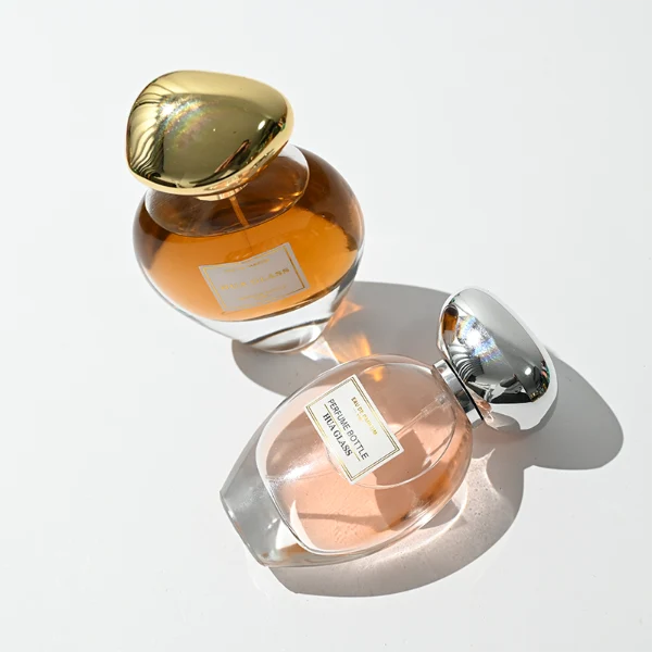 HUA0442 perfume bottle features a clear round curved glass body with a heavy base and is crowned with a modern premium pebble cobblestone-shaped silver or black plastic cap. Designed for wholesalers, it offers 30ml, 50ml, 75ml, and 100ml capacity options, delivering an elegant design that balances aesthetic refinement with durability for diverse fragrance lines.