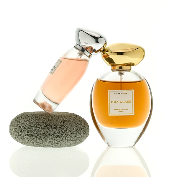HUA0442 perfume bottle features a clear round curved glass body with a heavy base and is crowned with a modern premium pebble cobblestone-shaped silver or black plastic cap. Designed for wholesalers, it offers 30ml, 50ml, 75ml, and 100ml capacity options, delivering an elegant design that balances aesthetic refinement with durability for diverse fragrance lines.