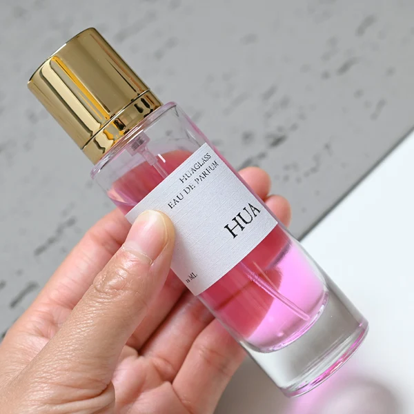 HUA0056 perfume bottle, heavy-base tall slender cylindrical round glass bottle with clear finish, featuring a wide wrapped paper label, a matching neck, and a tall cylindrical plastic cap with a smooth high-gloss shiny finish, elegant modern fragrance packaging design available in 30ml, 50ml, and 100ml