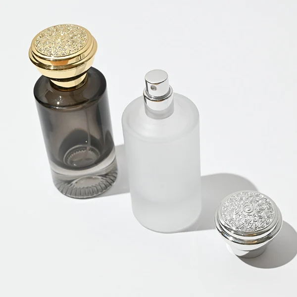 HUA0060 perfume bottle, heavy-base cylindrical round glass bottle with clear finish, featuring a matching neck and an ornate sculptural tiered crown plastic cap with a smooth high-gloss shiny finish, elegant modern fragrance packaging design available in 30ml, 50ml, and 100ml