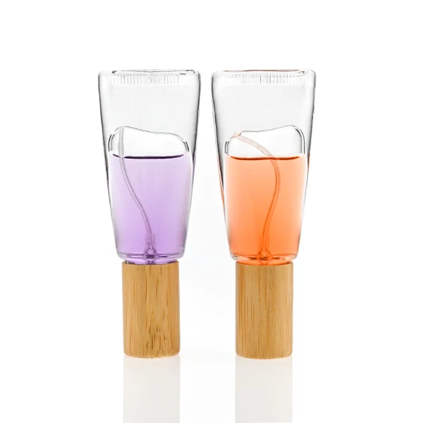HUA0297 perfume bottle, transparent colorless cosmetic tube-inspired glass body with asymmetrical sculptural silhouette and bamboo base, 10 ml liquid, integrated natural bamboo cap, clean glass surface without logo printing, artistic modern minimalist design, ideal for travel and gifting.